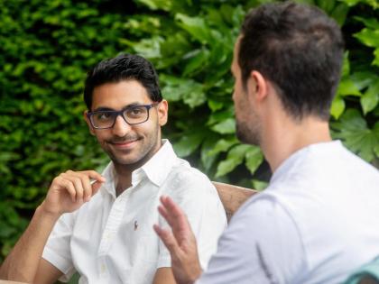 Two people sitting and talking. Both are in white tops.