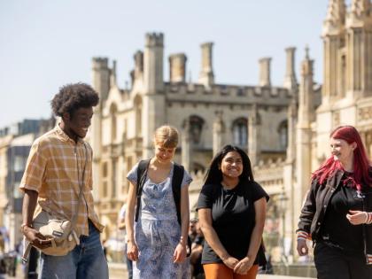 4 students walking with a historical Cambridge building behind them